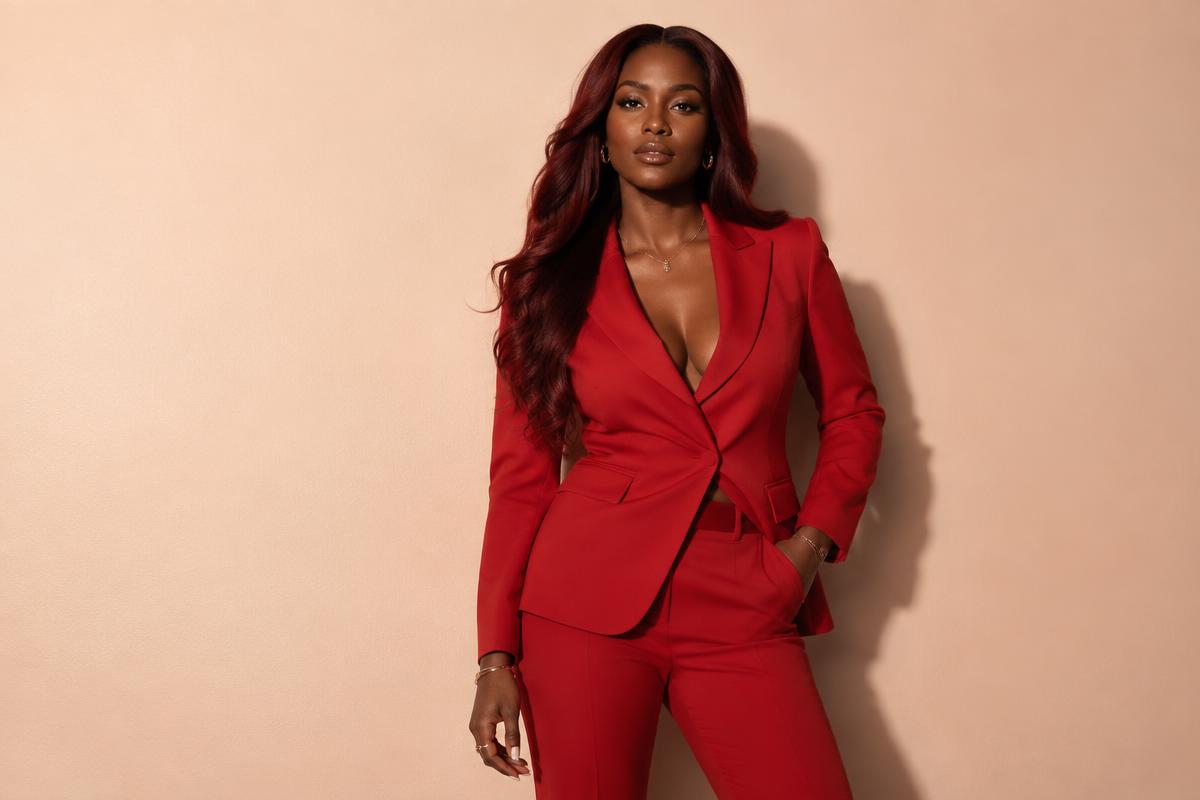 A fictional Black model with deep auburn hair in crimson tailoring